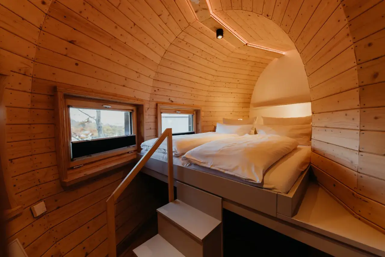 Gemütliches Schlafzimmer in Bad Harzburg, mit Holzwänden, einem Doppelbett und Fenstern mit Blick ins Grüne.
