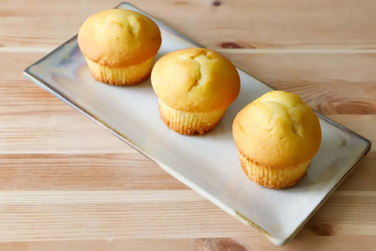 Tre soffici muffin allo yogurt dorati, pronti per essere gustati su un piatto rettangolare.