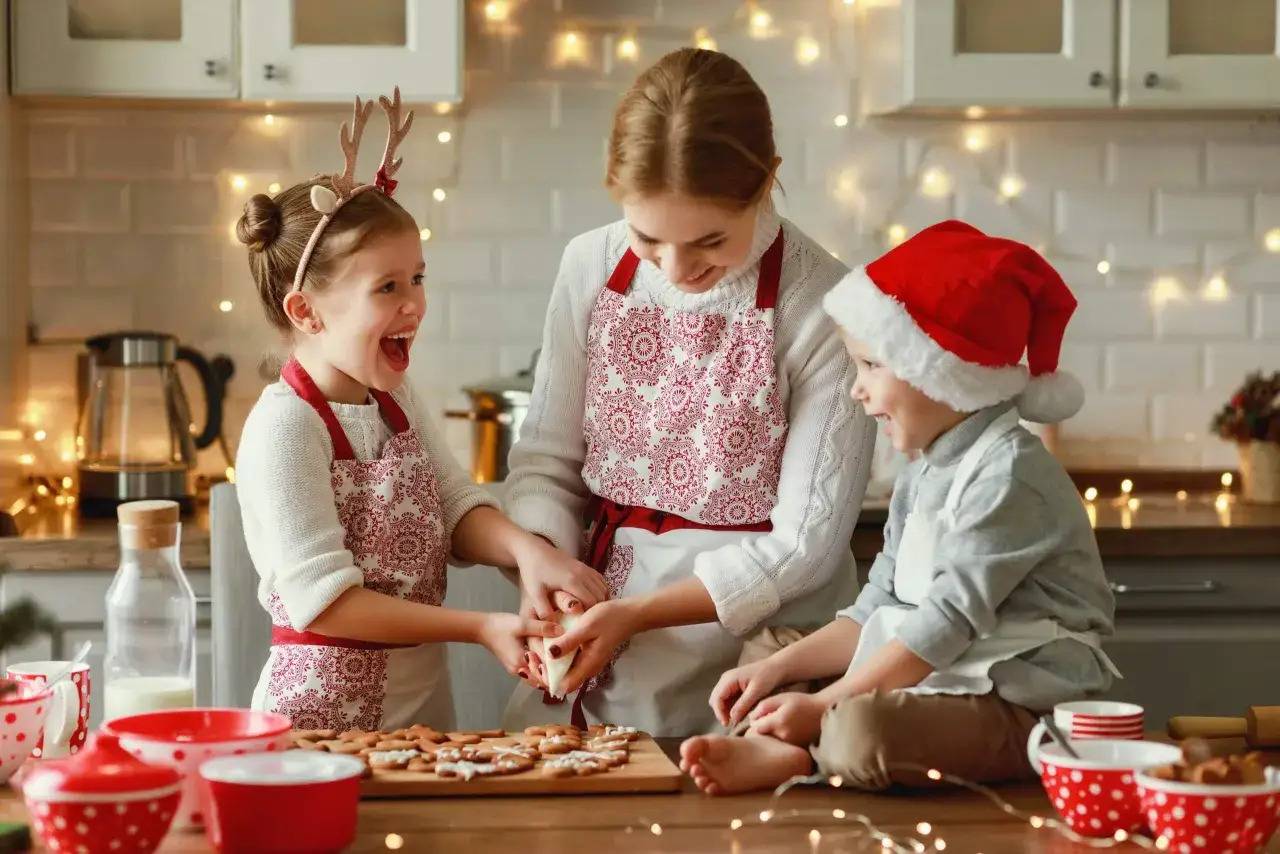 Mutter und Kinder backen Weihnachtspl&auml;tzchen. Die Kinder haben Spa&szlig; beim Verzieren der Kekse mit Zuckerguss.