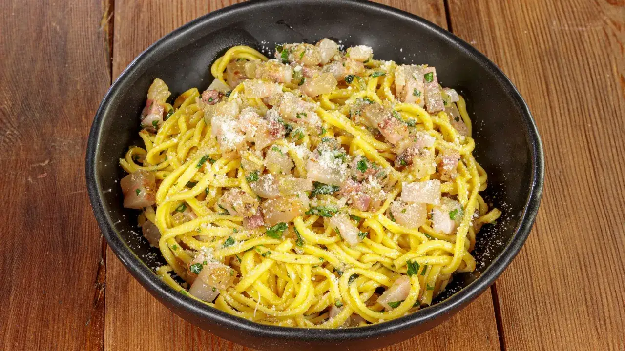 Spaghetti alla chitarra conditi con guanciale croccante, pecorino e prezzemolo fresco, un piatto che sa di tradizione.