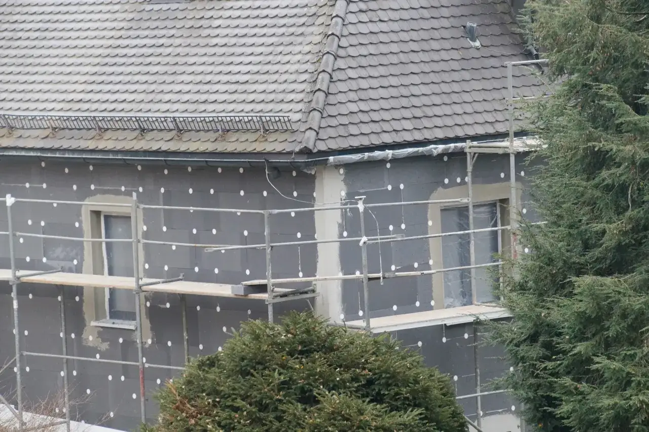 Hauswand mit **Isolierung Styropor** und Ger&uuml;st. Fenster sind verdeckt.