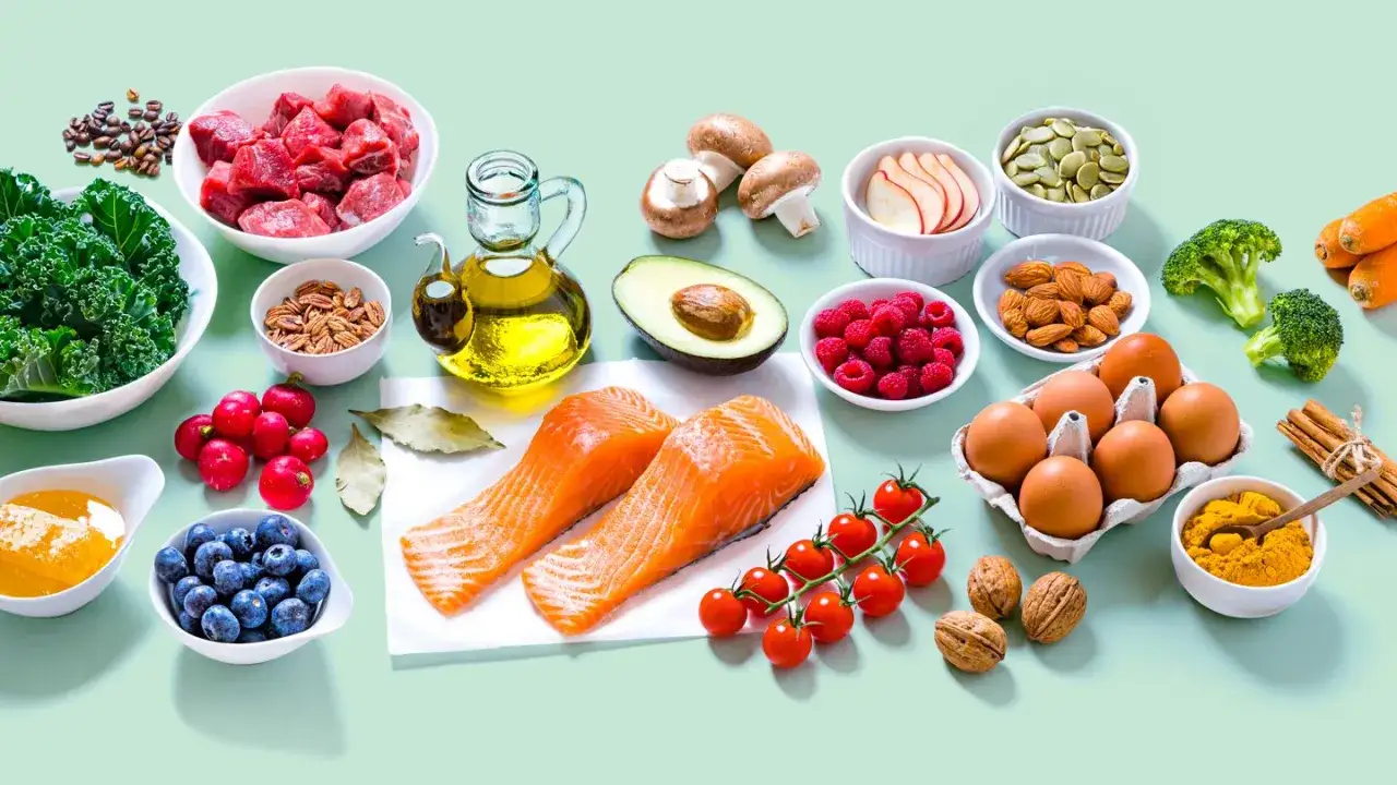 Składniki na dietę paleo: łosoś, mięso, jajka, awokado, jagody, orzechy, warzywa i oliwa z oliwek.