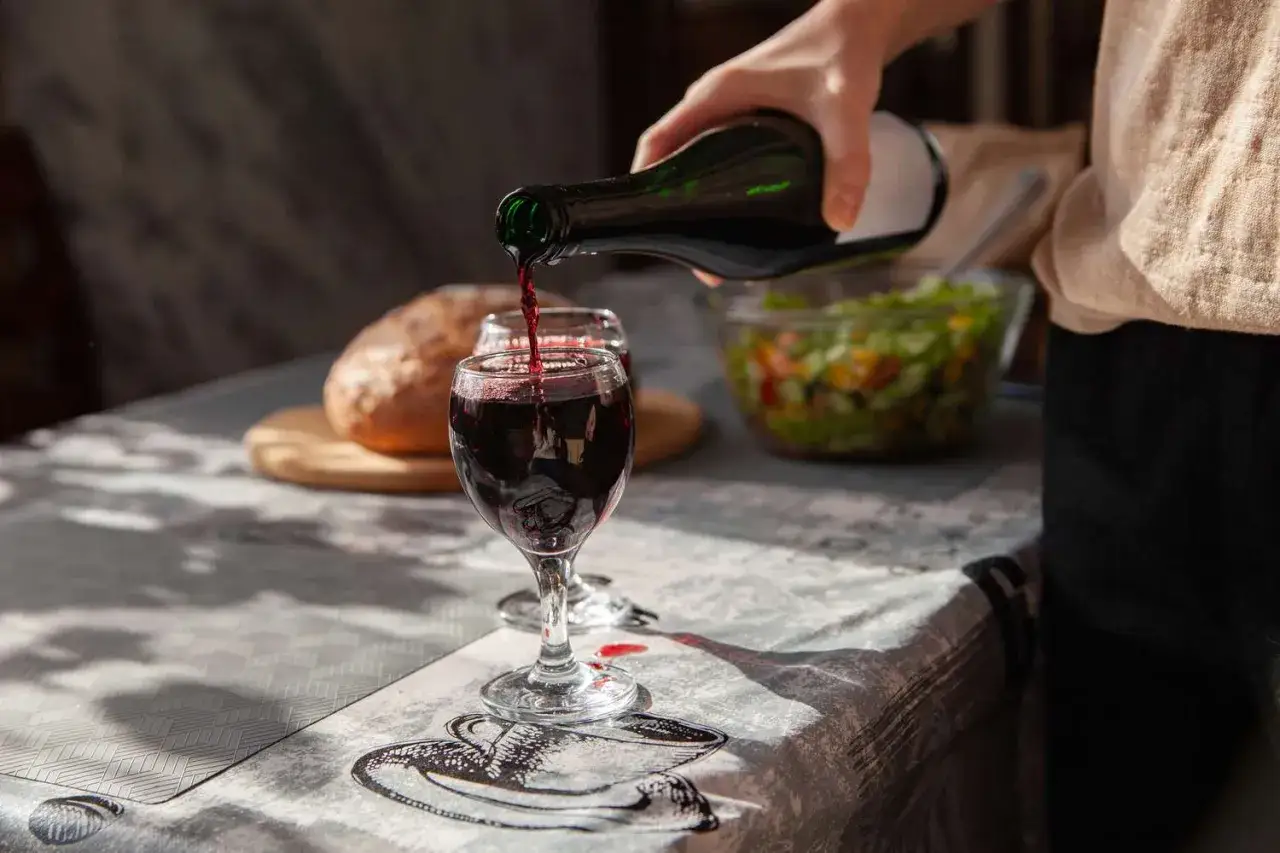Rotwein wird in ein Glas gegossen. Der **Nero d'Avola Geschmack** passt perfekt zu Brot und Salat.