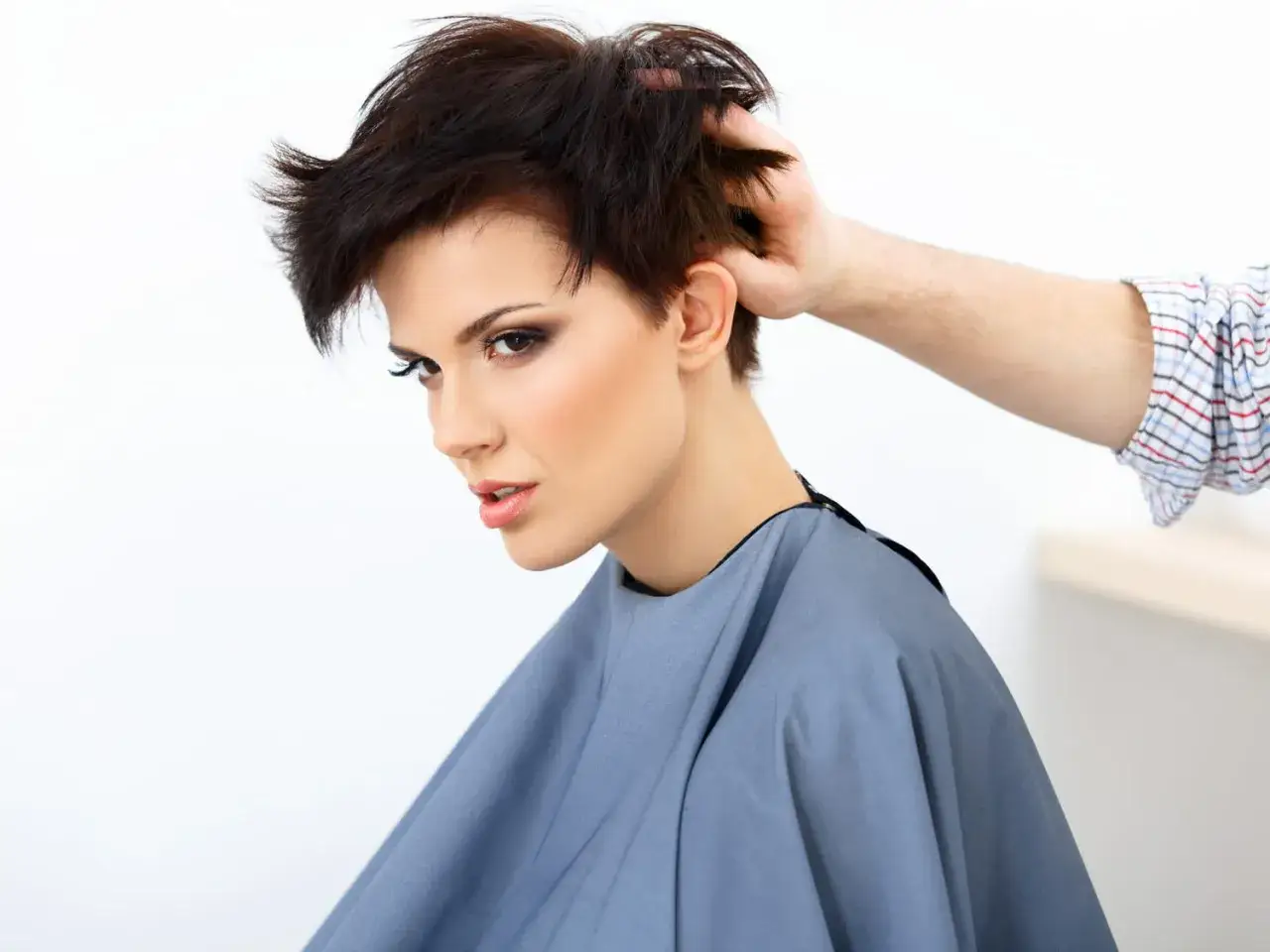 Une femme arbore une coiffure rock femme court, ses cheveux sombres sont coiffés avec audace.