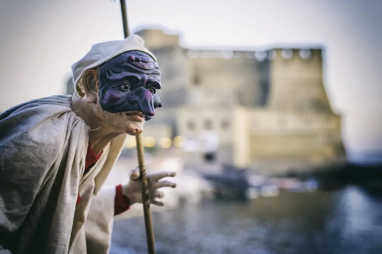 Maschera di Pulcinella, molto in napoletano, con Castel dell'Ovo sullo sfondo.