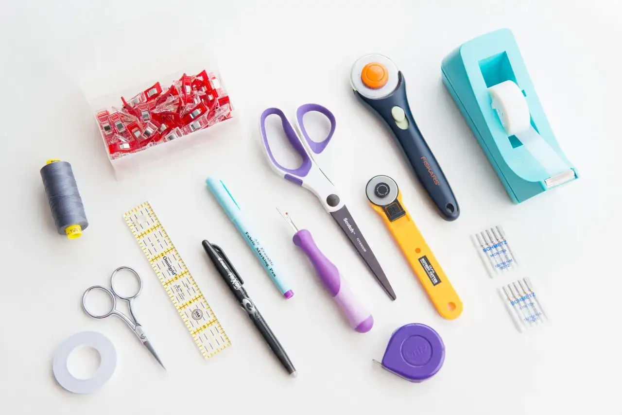 Tools for a sewing hobby: thread, clips, scissors, rulers, marking pen, seam ripper, rotary cutters, needles, tape, and measuring tape.