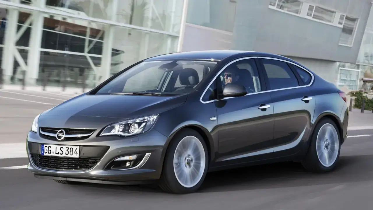 Elegancki Opel Astra J w ruchu. Kierowca w okularach prowadzi auto. Sprawdź opel astra j wymiary.