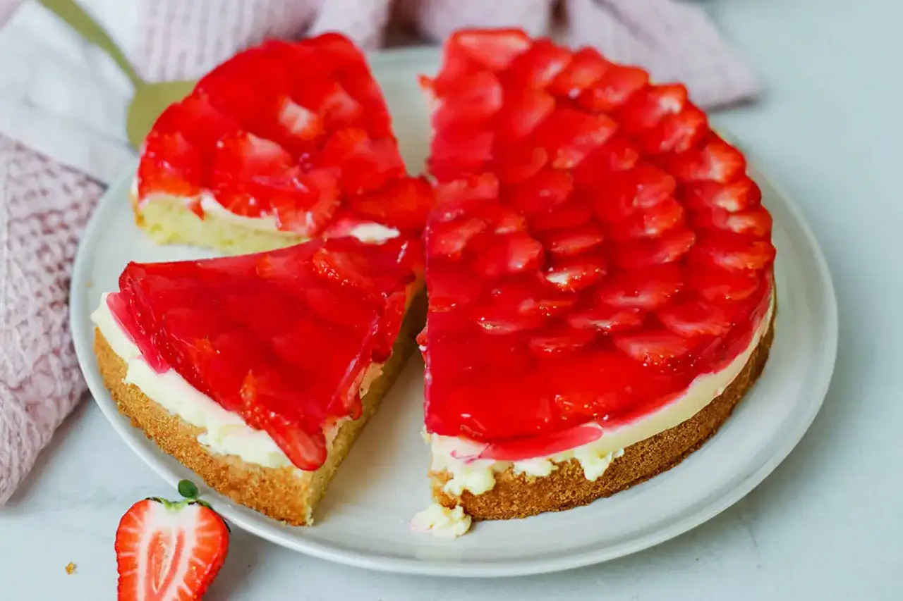 Ein saftiger Erdbeerkuchen mit Pudding und rotem Tortenguss, belegt mit frischen Erdbeerscheiben.