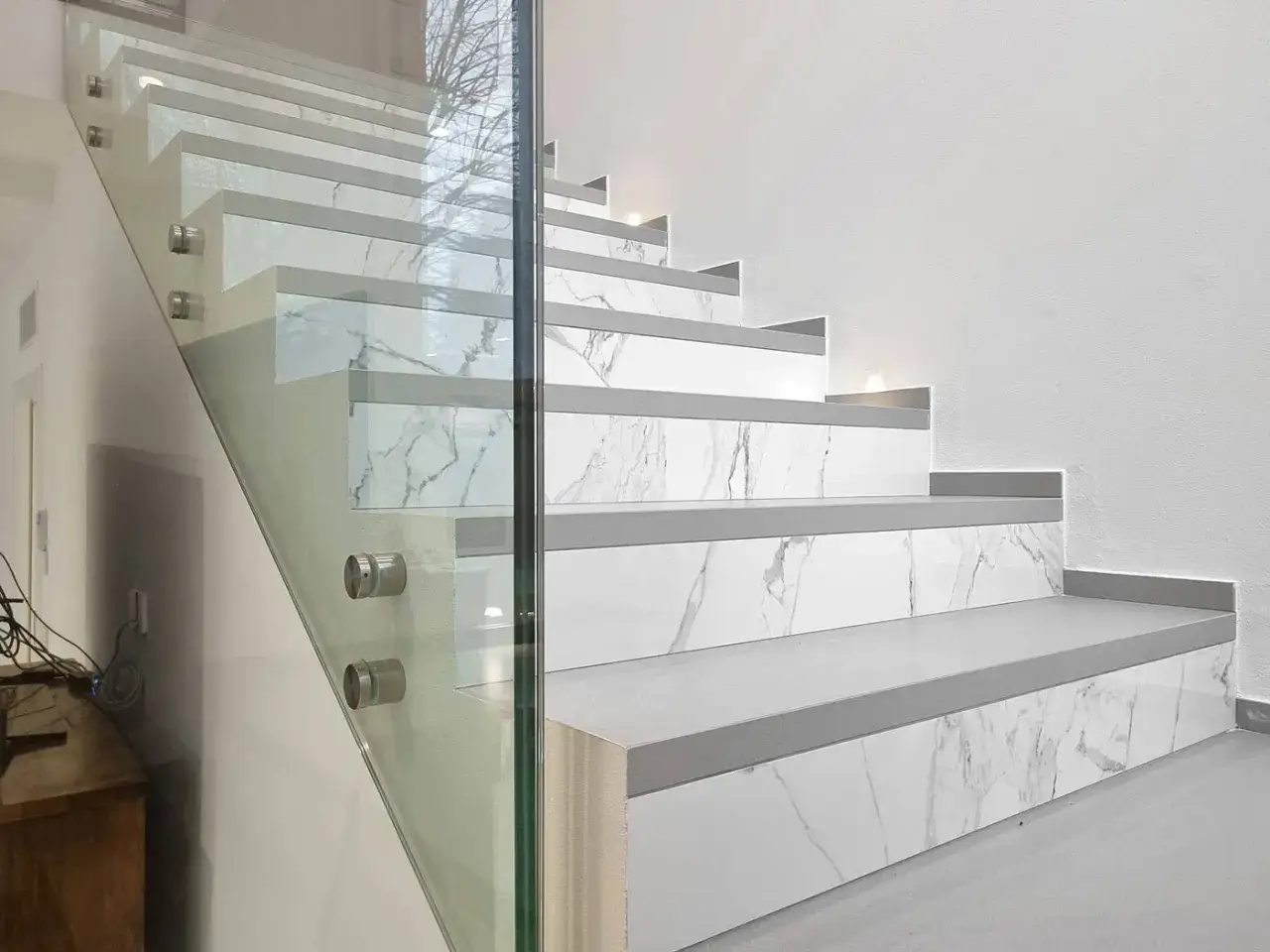 Moderna scala con gradini in marmo e vetro. Soluzioni eleganti per chi cerca una scala troppo ripida ma di design.