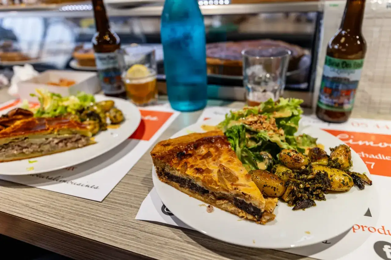 Deux assiettes de spécialités Limoges : une part de tourte garnie et une autre de quiche avec salade et pommes de terre.