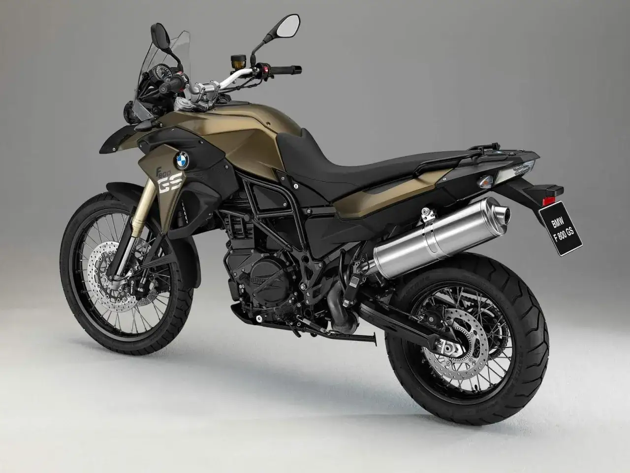 Złoty motocykl BMW F 800 GS z czarnym siedzeniem i akcesoriami, gotowy na przygodę.