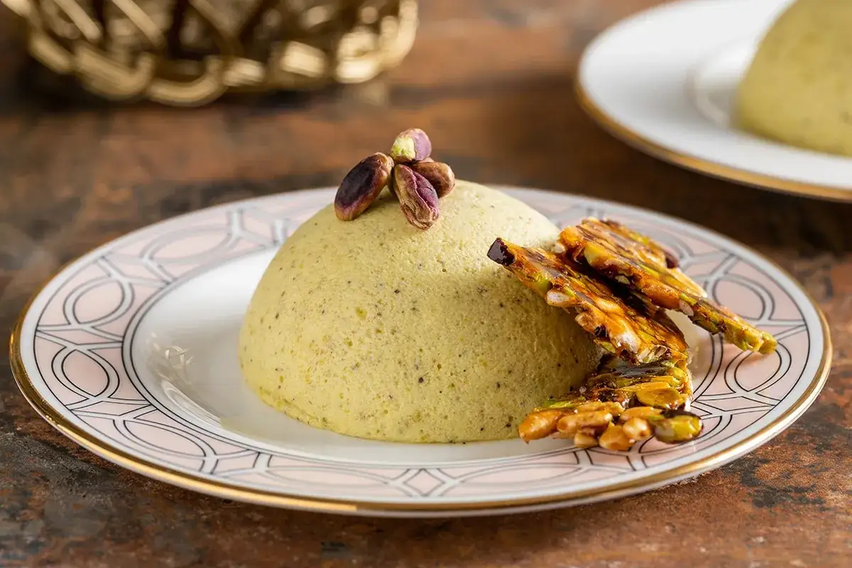 Un soffice parfait al pistacchio, guarnito con pistacchi interi e croccante caramello di frutta secca.