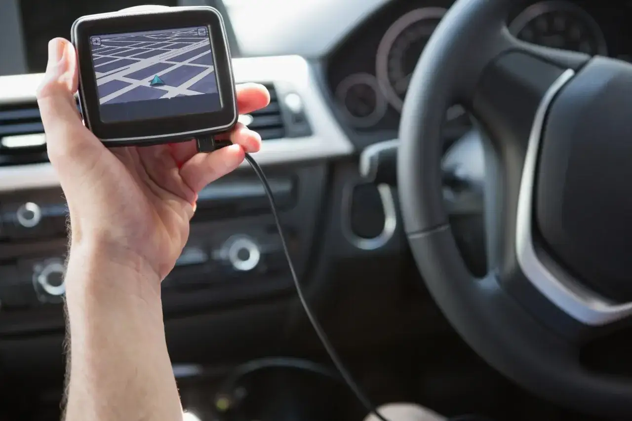 Dłoń trzyma nawigację GPS, pokazującą trasę. Tak działa transmiter, ułatwiając podróżowanie.