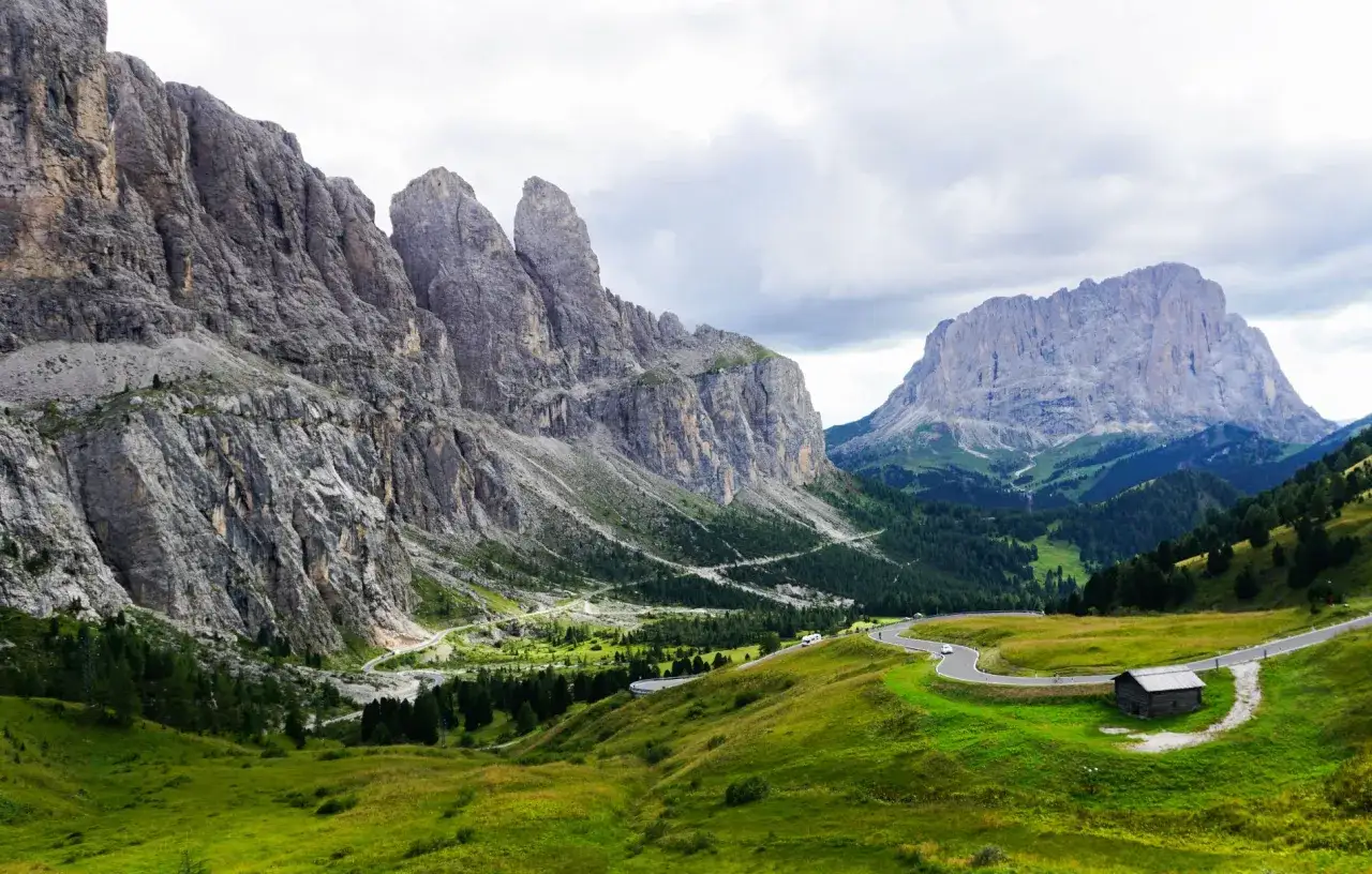 Góry Dolomity, malownicza droga wijąca się przez zielone wzgórza, a w oddali potężne szczyty. San Pellegrino pogoda zapowiada się na piękną podróż.
