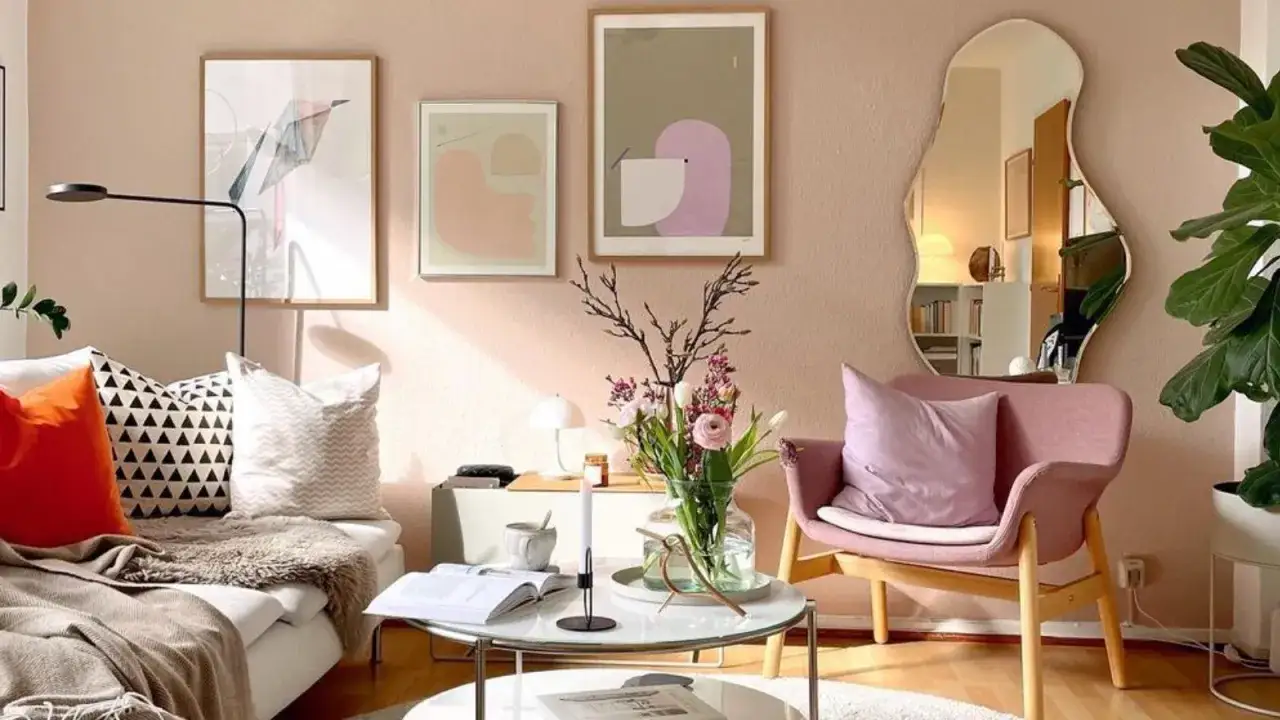 Gemütliches Wohnzimmer im **danish pastel** Stil mit rosa Sessel, Couch, Blumen und Kunstwerken an der Wand.
