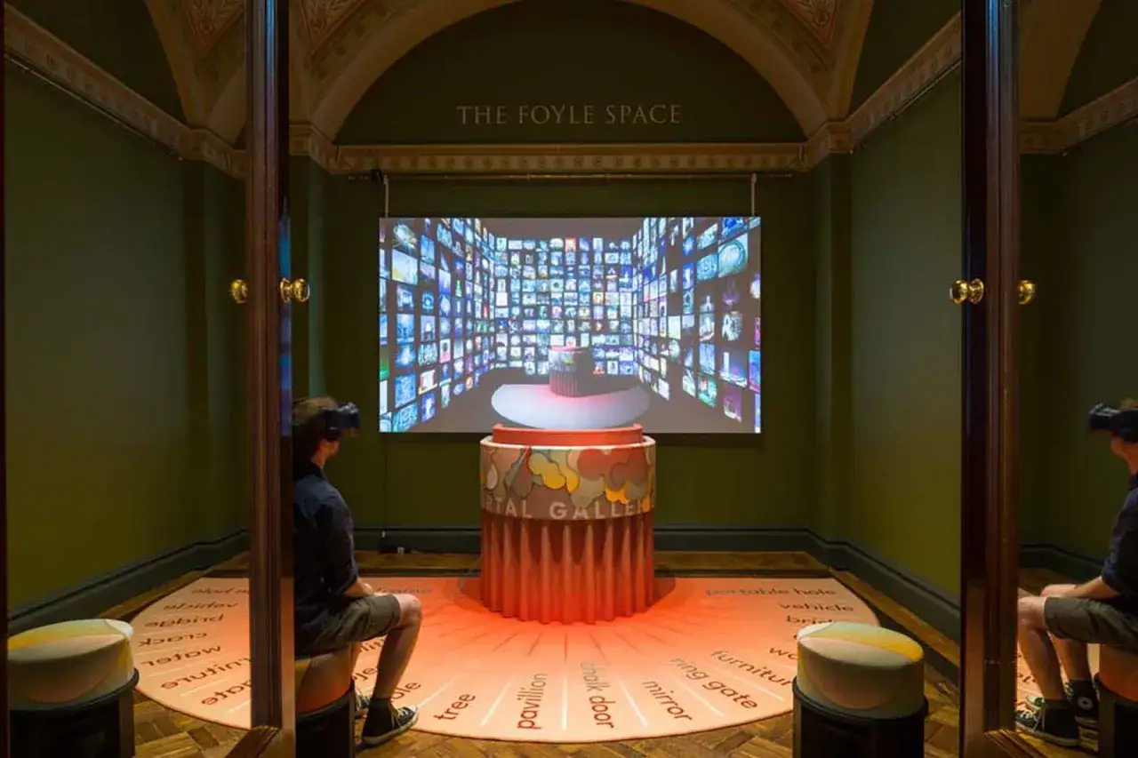 Besucher in VR-Brillen erleben interaktive Kunstwerke nachstellen. Ein Bildschirm zeigt eine Wand aus Bildern, w&auml;hrend W&ouml;rter auf dem Boden zum Erkunden einladen.