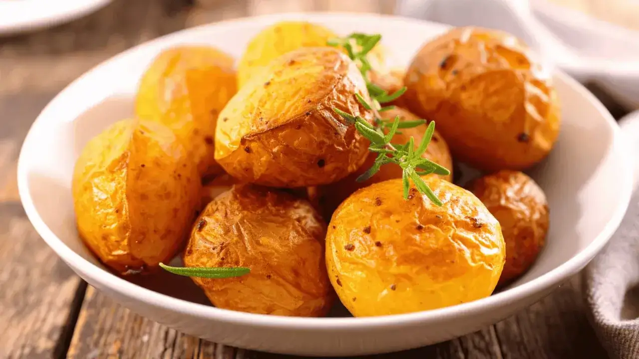 Pommes de terre rôties au four, parfaites pour accompagner une raclette. Elles sont dorées et garnies de romarin frais.
