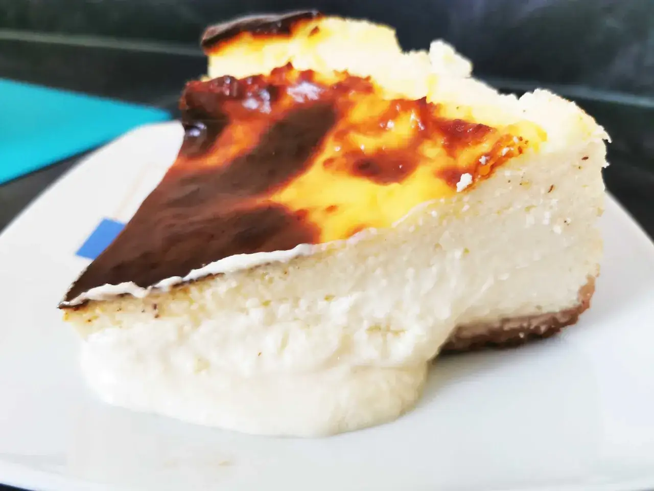 Una porción de tarta de queso con la parte superior quemada y cremosa, lista para ser disfrutada.