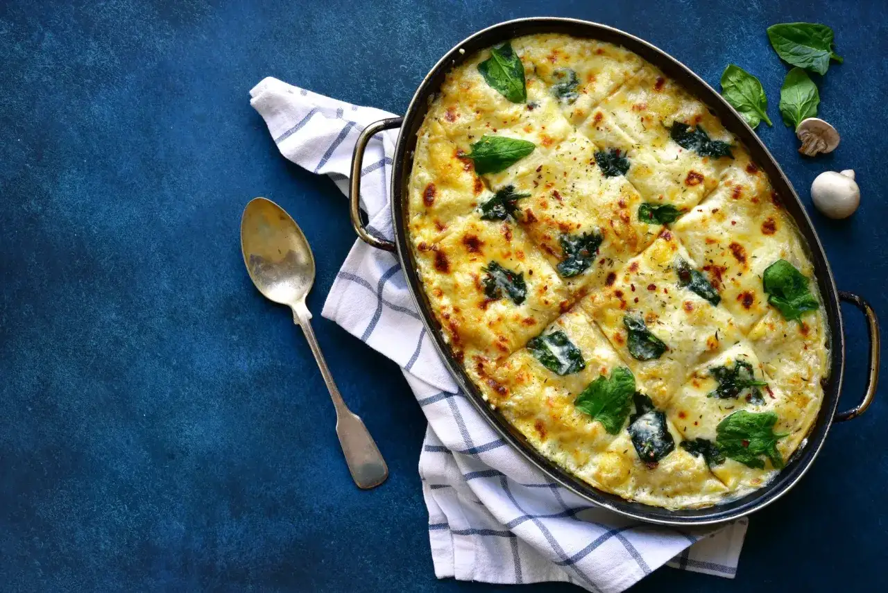 Lasagnes poulet champignons gratin&eacute;es, garnies d'&eacute;pinards frais et de fromage fondant, pr&ecirc;tes &agrave; &ecirc;tre d&eacute;gust&eacute;es.