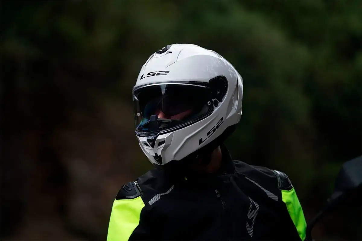 Un motociclista indossa un casco integrale bianco LS2, un esempio di diversi tipi di casco per la sicurezza su strada.