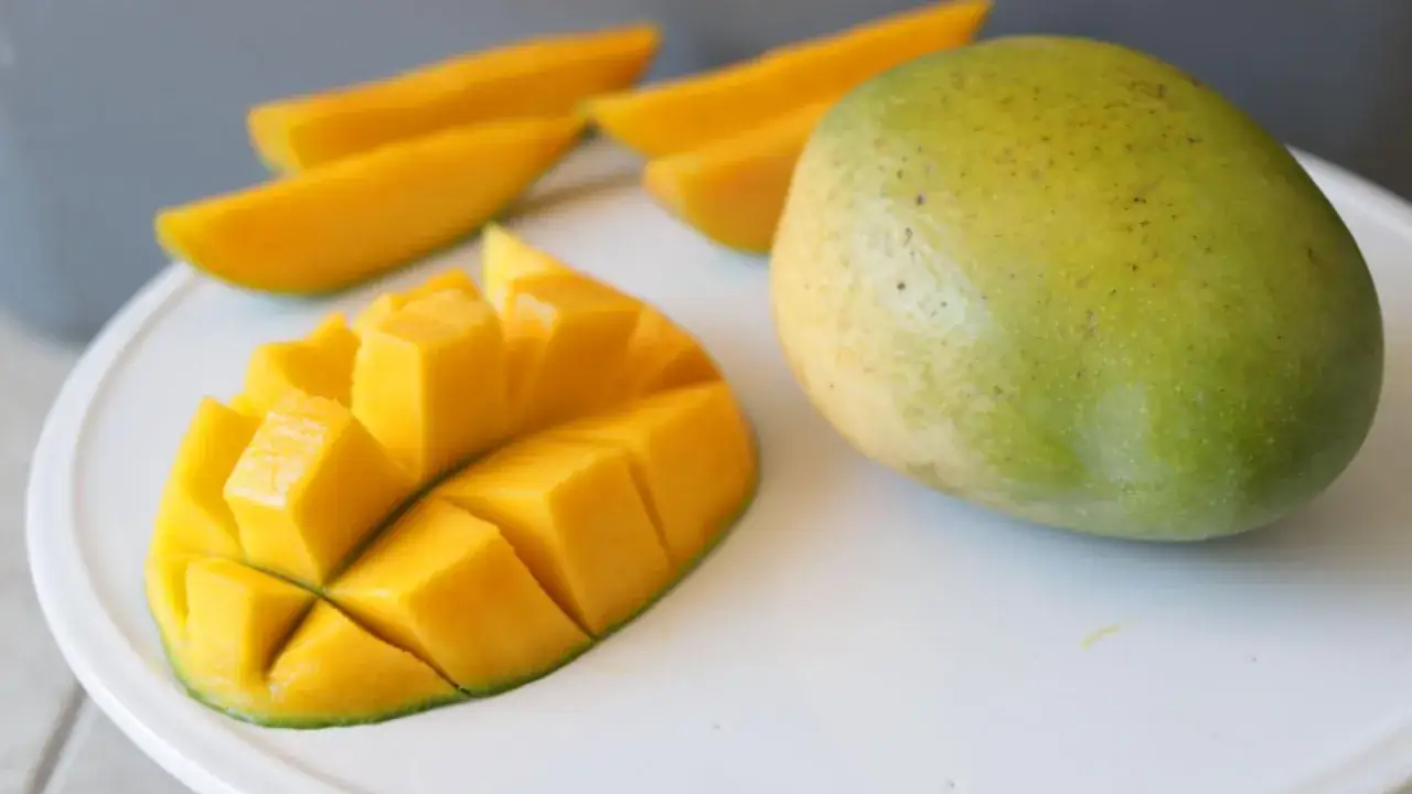 Dojrzałe mango w ciąży, pokrojone w kostkę i w plasterkach, prezentuje swoje soczyste, złociste wnętrze.