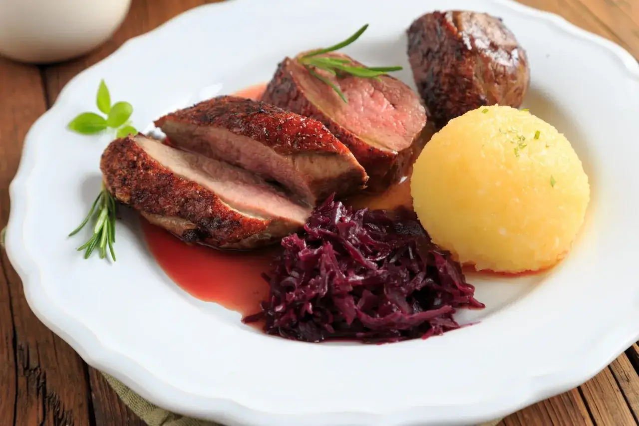 Magret de canard tranch&eacute;, servi avec chou rouge et une quenelle. Un plat savoureux, parfait pour se demander que boire avec du magret de canard.