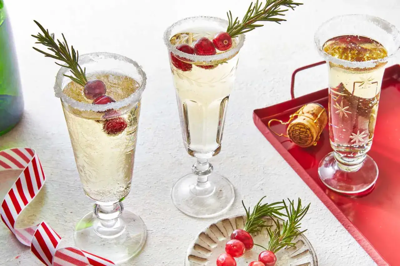 Elegancki mimoza drink przepis: kieliszki z szampanem, cukrowym rantem, żurawiną i rozmarynem. Idealny na święta.