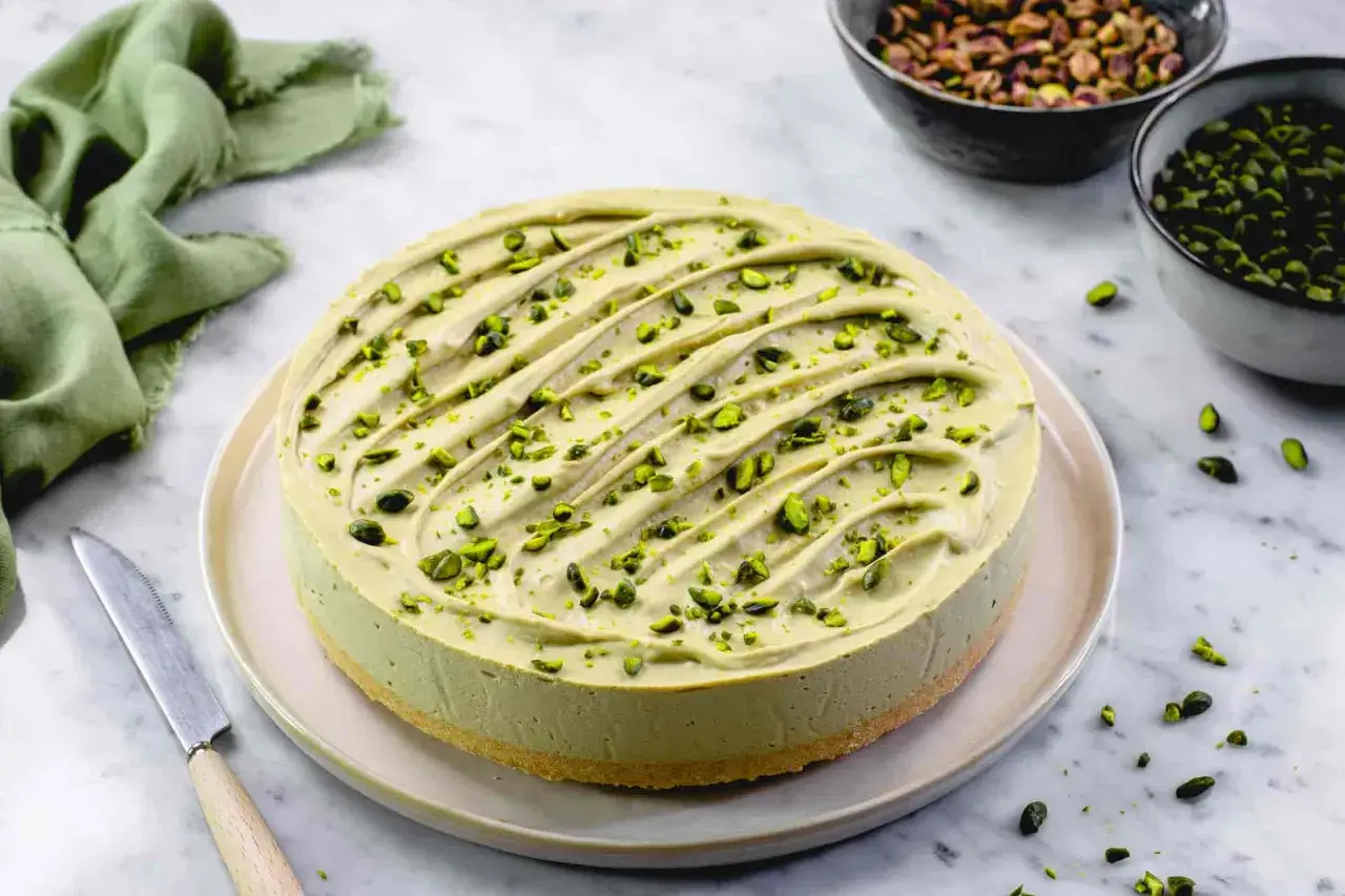Delizioso cheesecake al pistacchio, guarnito con granella verde brillante. Un'opera d'arte culinaria pronta da gustare.