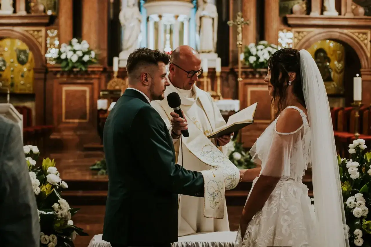 Para Młoda podczas ceremonii w kościele. Kapłan czyta z księgi, co daje ślub kościelny: sakrament i błogosławieństwo.