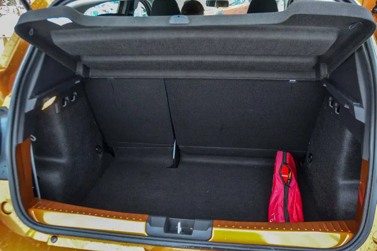 Pusta przestrzeń bagażnika Dacii Sandero, gotowa na bagaże. W rogu czerwona torba z wyposażeniem.