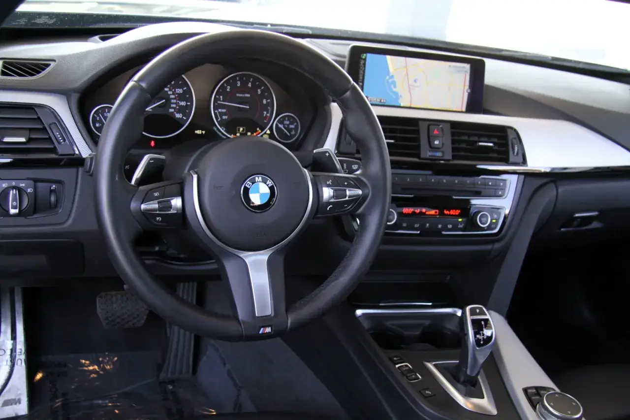 Wnętrze BMW F32 435i: kierownica, deska rozdzielcza z nawigacją i panelem klimatyzacji, dźwignia zmiany biegów.