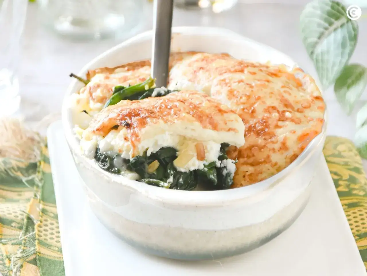 Deliciosa lasa&ntilde;a de espinacas con queso gratinado, servida en un cuenco blanco.