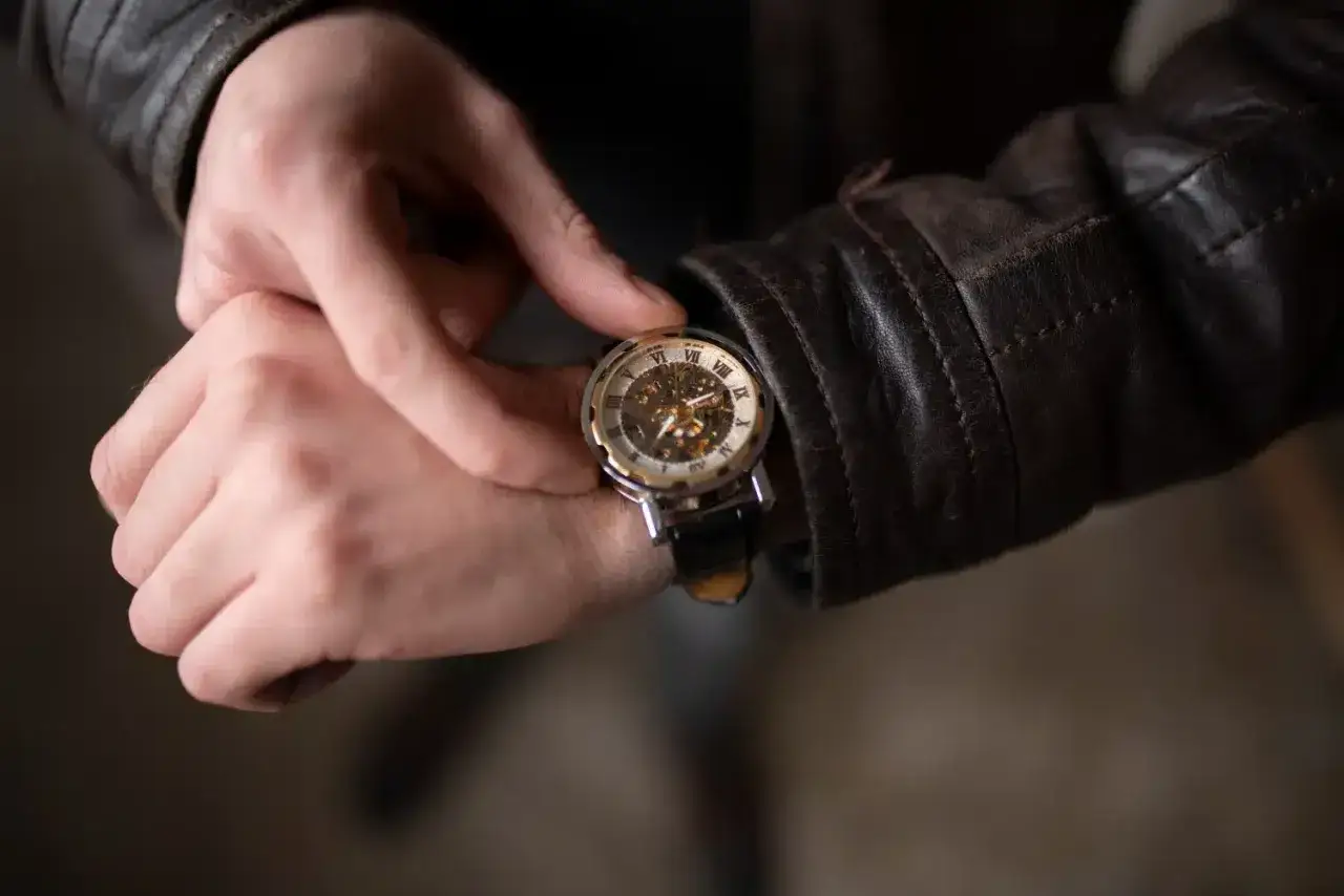 Un uomo con giacca di pelle controlla un orologio scheletrato, uno dei tanti tipi di orologi che mostrano la complessit&agrave; meccanica.
