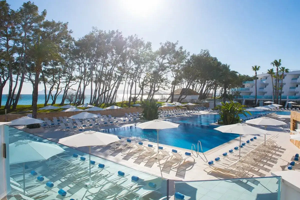 Disfruta del sol y las **iberostar waves playa de muro** junto a la piscina. Tumbonas, sombrillas y el mar azul te esperan.