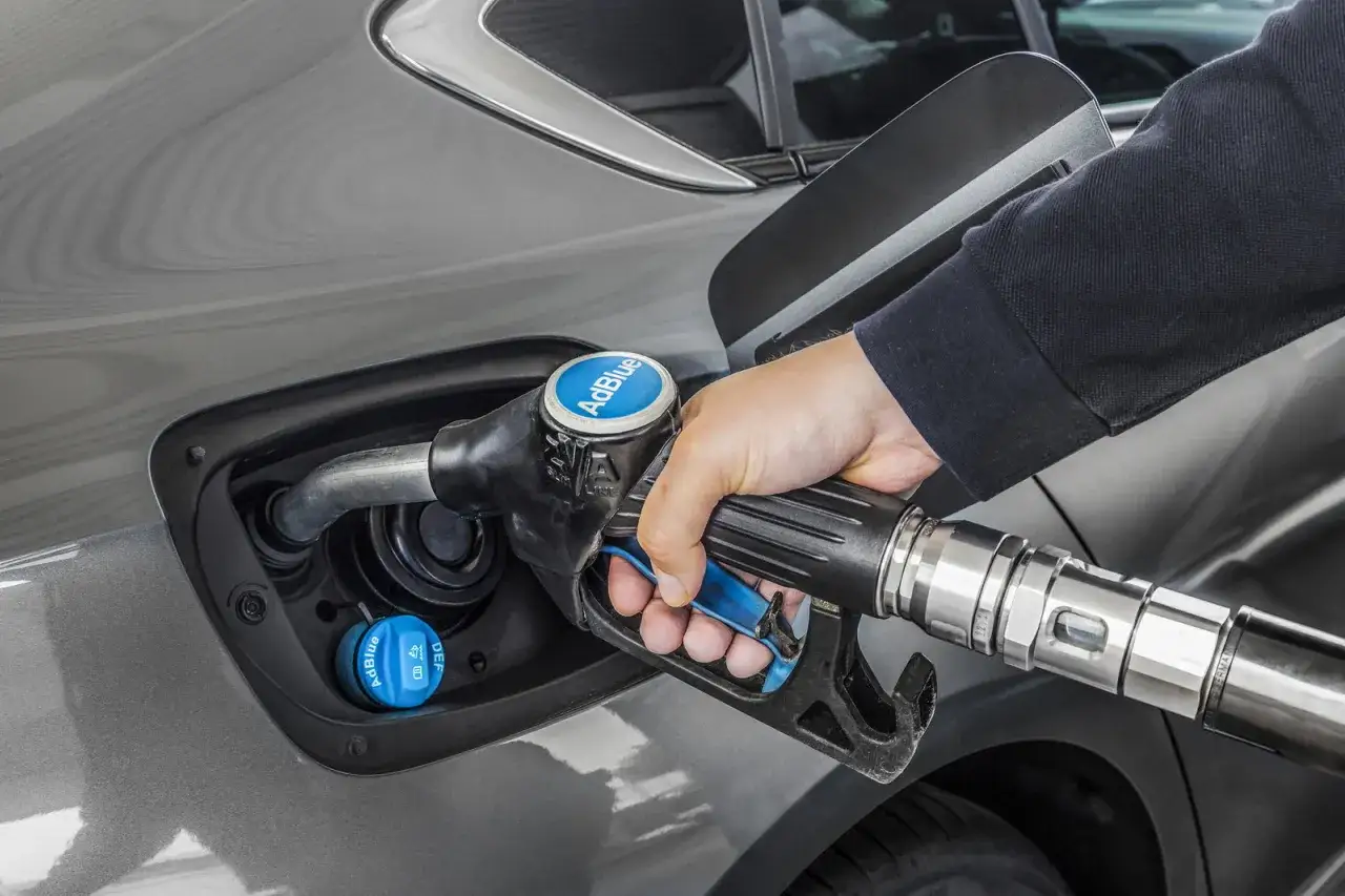 Rifornimento di AdBlue per un'auto diesel. La mano tiene la pistola erogatrice blu con il logo AdBlue.