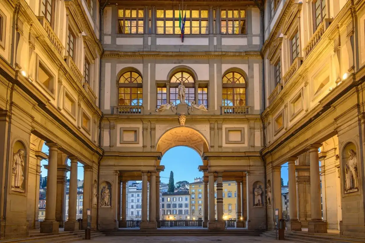 The Uffizi Gallery's courtyard at dusk, with its grand arches and statues, offers a glimpse of Florence's architectural splendor, rivaling the Accademia.