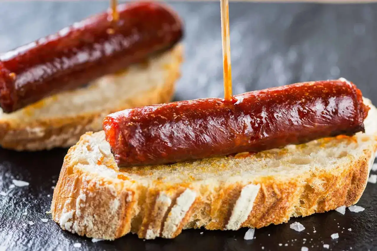 Pinchos de chorizo, una deliciosa comida típica de Navarra, servidos sobre pan rústico.
