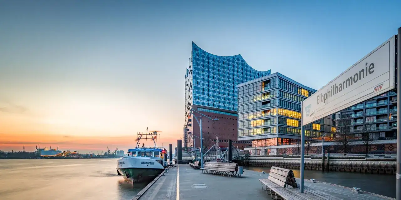 Die Elbphilharmonie, eine architektonische Attraktion Hamburgs, spiegelt sich im Wasser. Ein Schiff liegt am Kai.