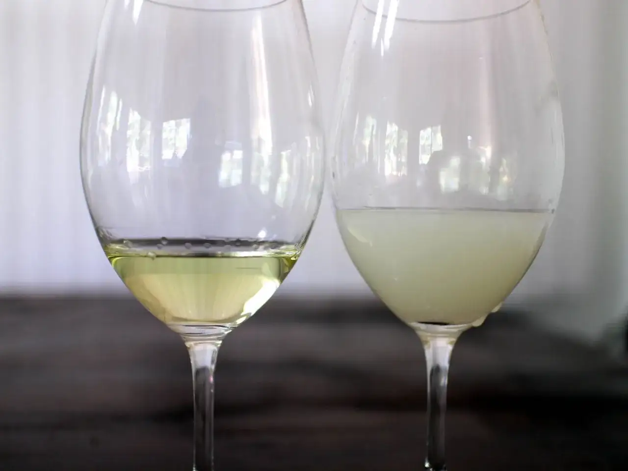 Zwei Weingl&auml;ser: eins mit klarem, gelblichem Inhalt, das andere mit tr&uuml;bem, milchigem Inhalt, der an Ouzo Geschmack erinnert.