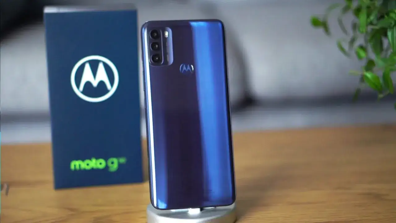 Elegancki, niebieski moto g 50 na stojaku, obok pudełka z logo Motorola.