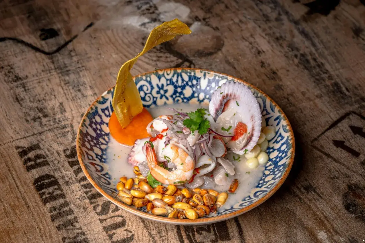 Pyszne ceviche z krewetką, ośmiornicą i przegrzebkiem, podane z kukurydzą i platanem. Smaki Peru na talerzu.