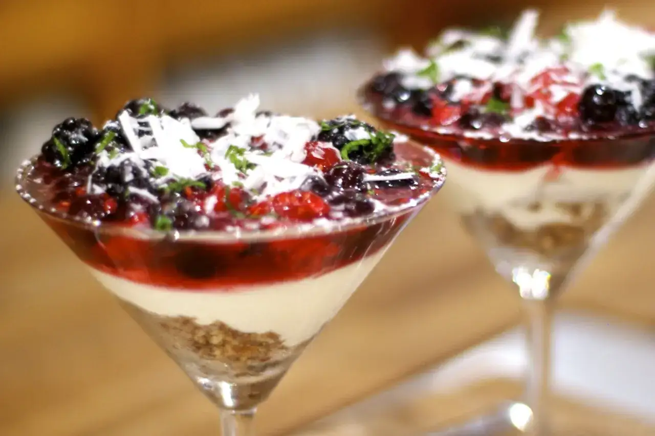 Två glas med en enkel dessert fyllda med bär, grädde och krispigt. En perfekt avslutning på måltiden.
