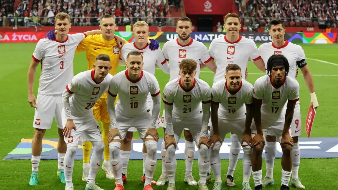 Drużyna piłkarzy z polskimi korzeniami w białych strojach z orłem na piersi. Duma narodowa na boisku.
