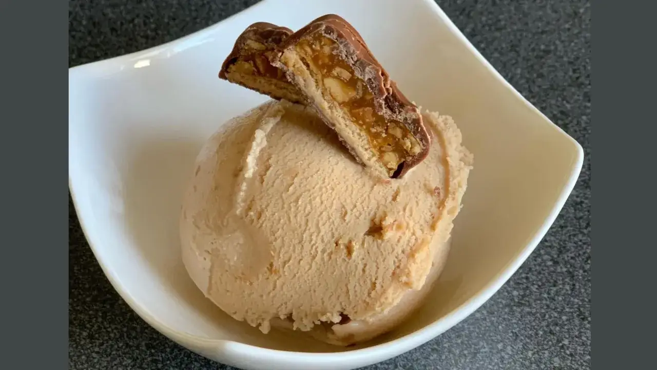 Ein cremiges Snickers Eis selber machen ist einfacher als gedacht! Hier ist das Ergebnis: eine Kugel Eis mit einem Stück Snickers obendrauf.