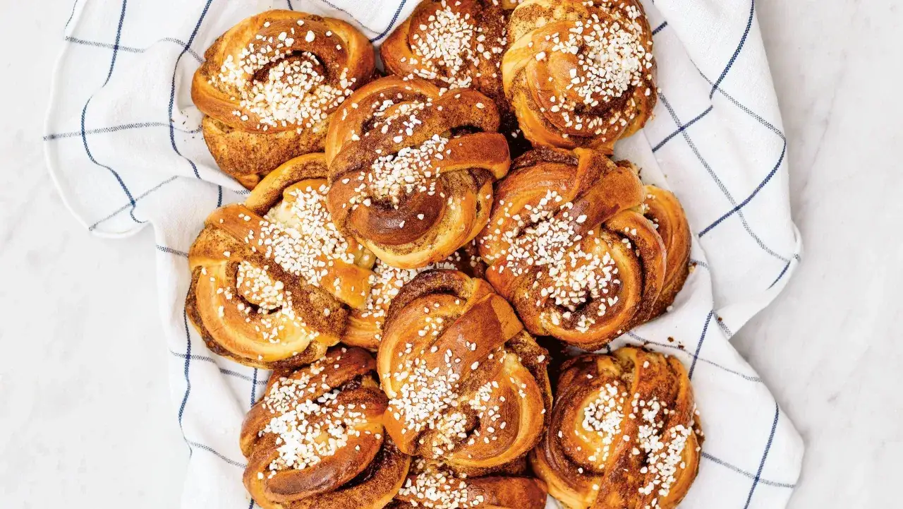 En h&ouml;g med gyllene kanelbullar, toppade med p&auml;rlsocker, som om Camilla Hamid precis bakat dem.