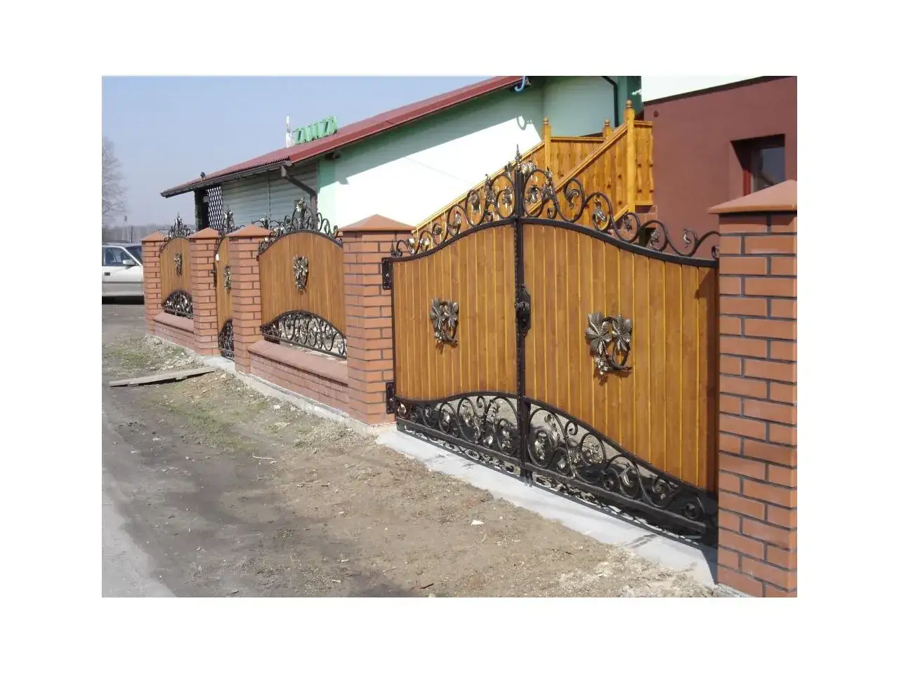 Eleganckie projektowanie ogrodzenia z drewnianymi panelami, kutymi elementami i ceglanymi słupkami.