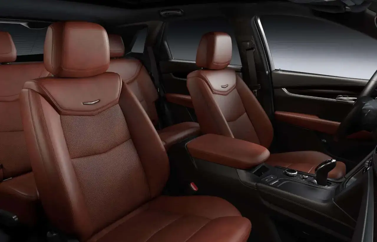 Wnętrze Cadillac XT5 z brązową, perforowaną skórą. Luksusowe fotele i konsola środkowa.