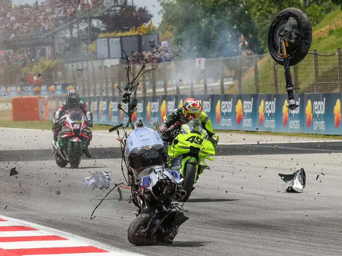 Caos en MotoGP: una moto se eleva tras un accidente, con escombros volando y otros pilotos intentando esquivar el desastre. El holeshot motogp se vio interrumpido.