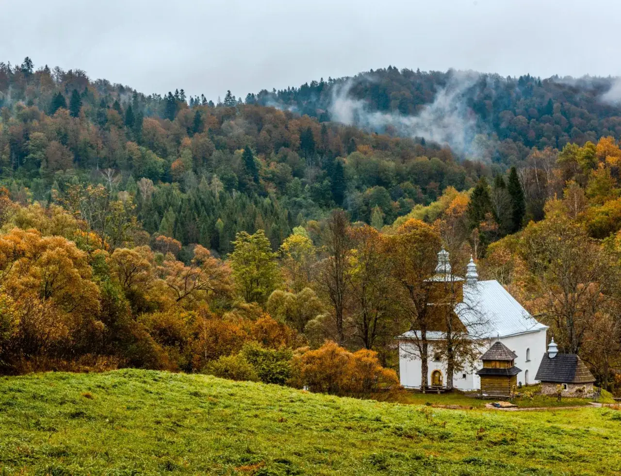 Jesienna mgła otula lasy nad Łopienką. Biała cerkiew z drewnianą dzwonnicą g&oacute;ruje nad kolorowym krajobrazem.