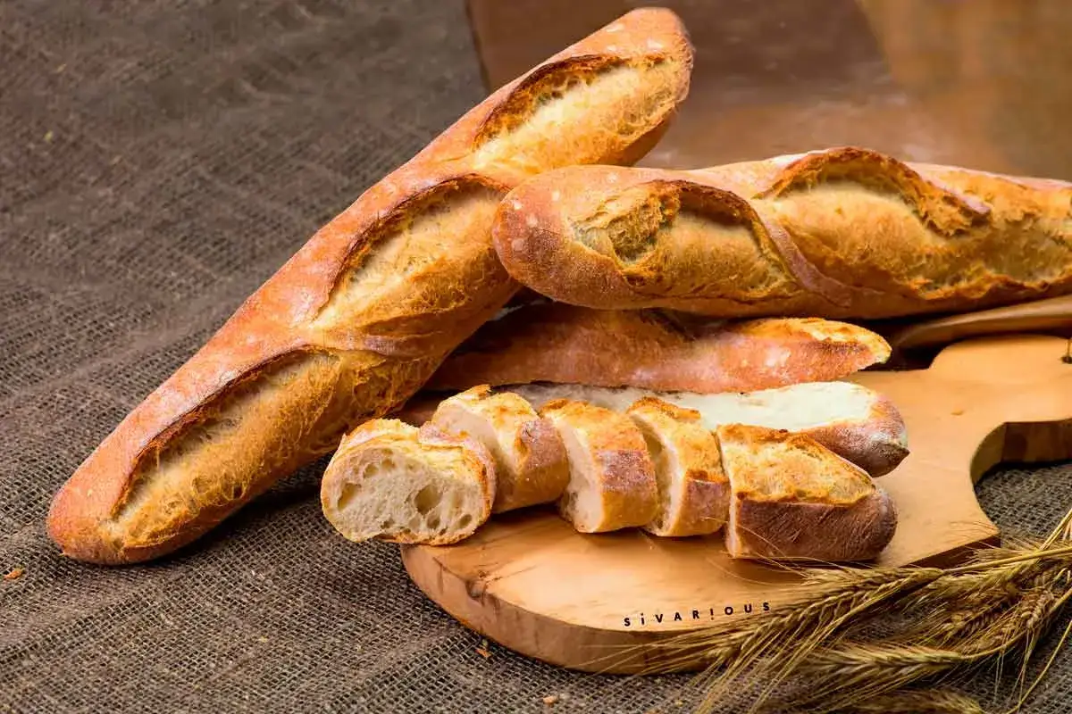 Bagettes doradas y crujientes, algunas enteras y otras cortadas, listas para disfrutar. Aprende como hacer baguette casera.